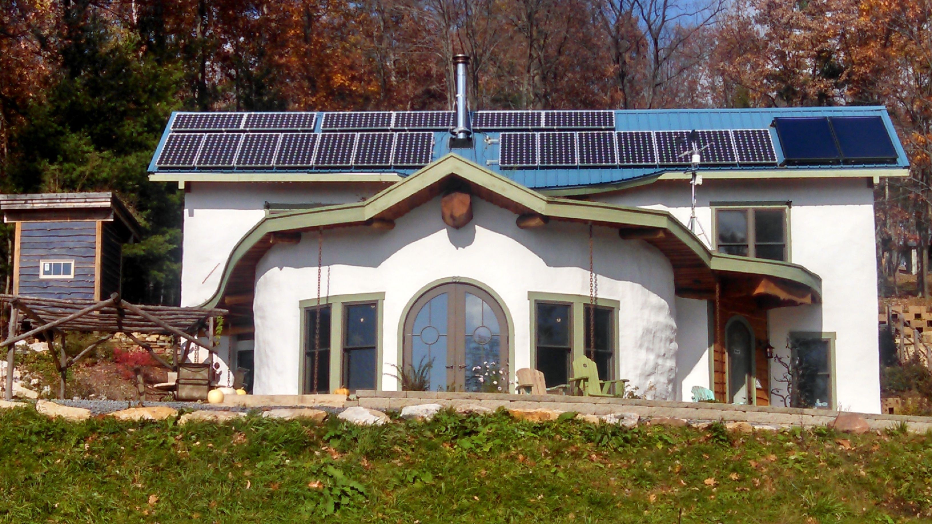 A modern house with solar panels, a large arched window, and a stone facade.