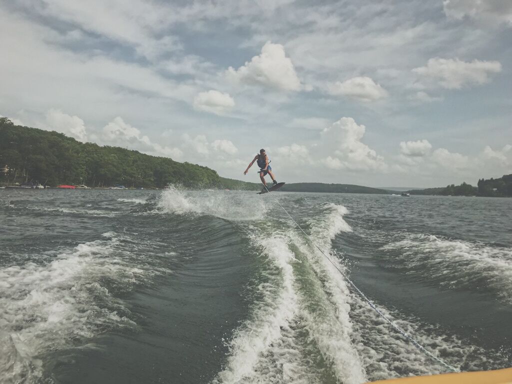 A person wakeboarding on a body of water with waves created by a boat.