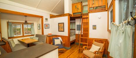 A cozy cabin interior with a loft bed, a dining area, and a seating space.