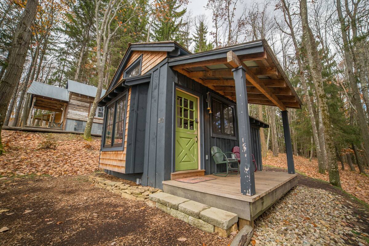 A cabin with a green door, a porch, and a stone pathway leading to it.