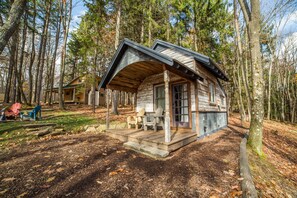 A rustic cabin with a porch, surrounded by trees.
