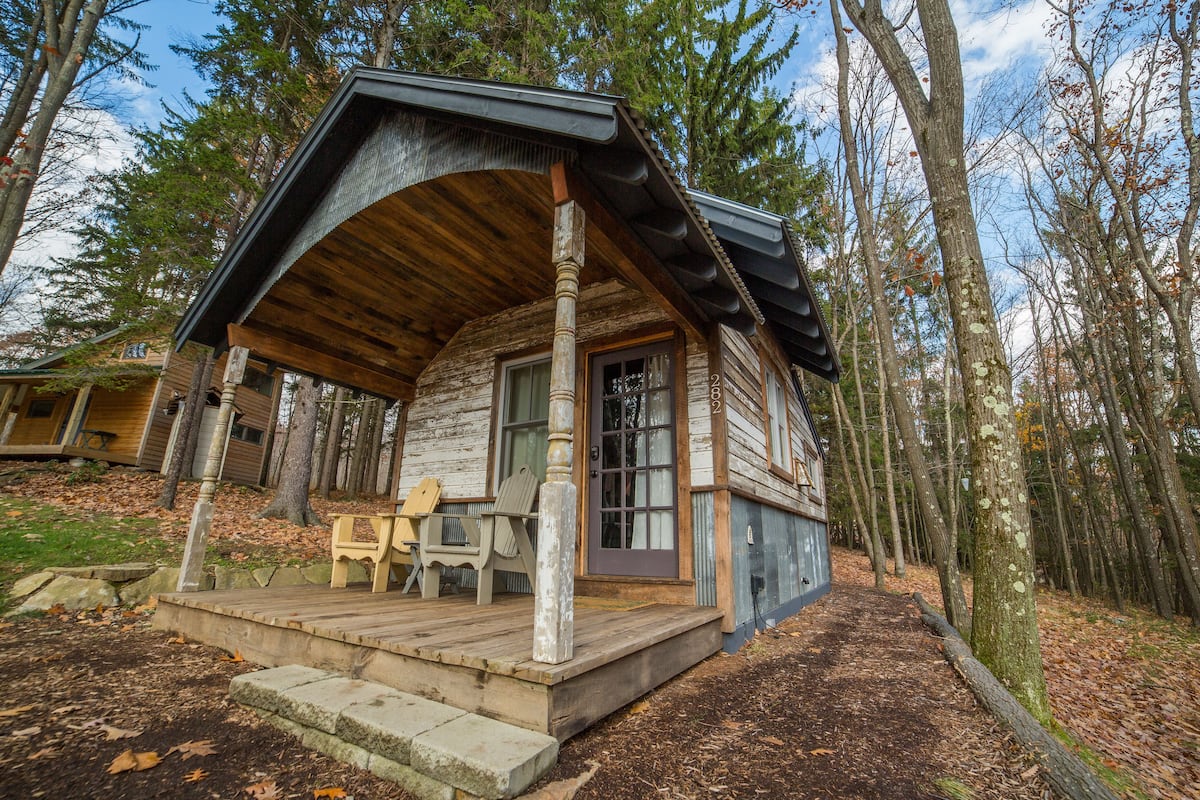A rustic cabin with a wooden porch, a door, and a window.