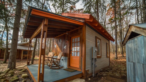 A rustic cabin with a porch, a rocking chair, and a small deck. - Blue Moon Rising (McHenry)