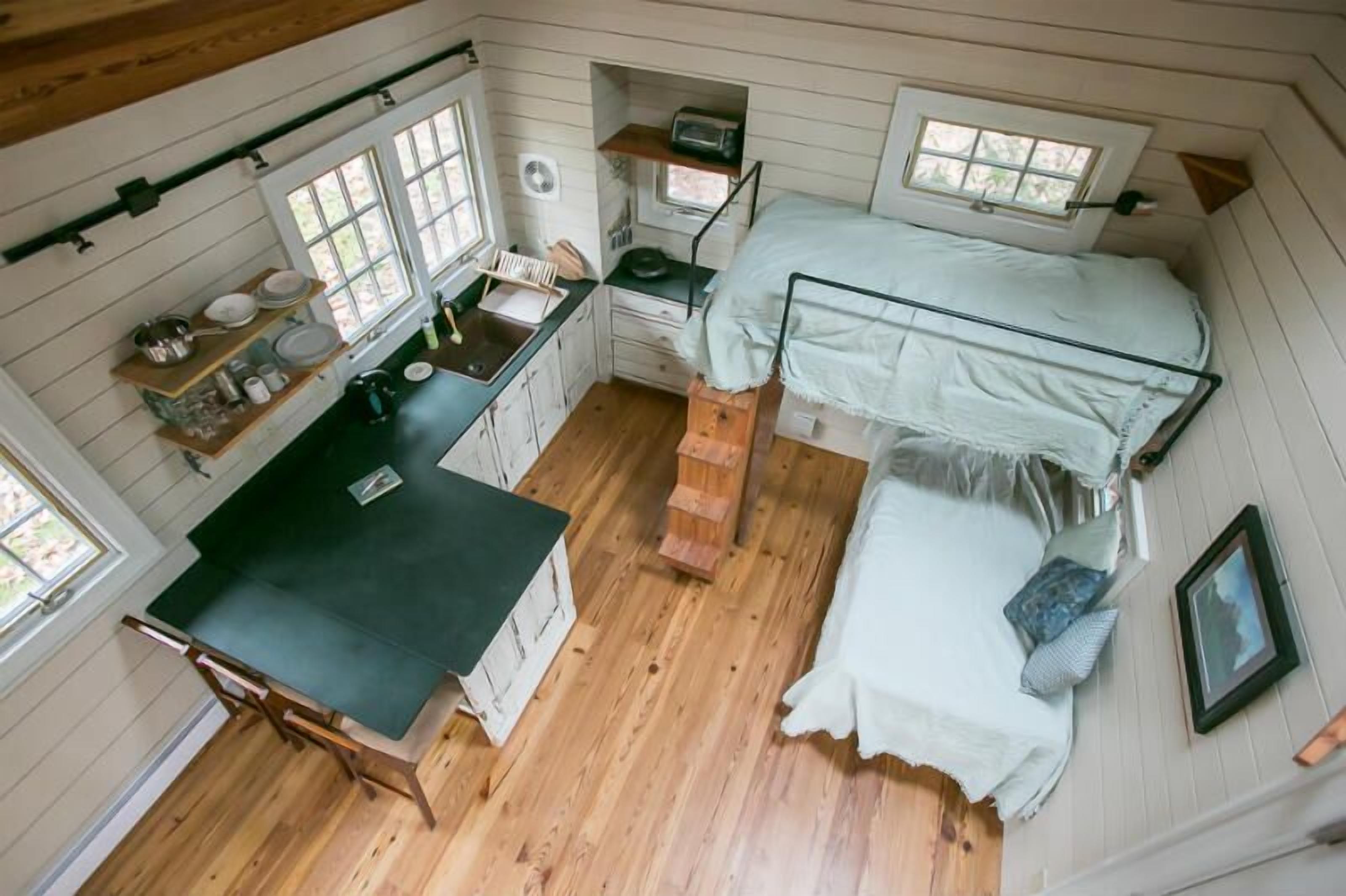 A compact room with a bunk bed, a small kitchenette, and a window.