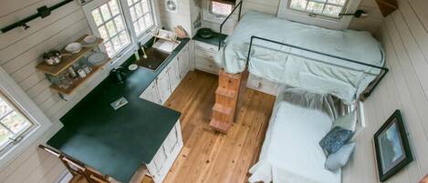A compact room with a bunk bed, a small kitchenette, and a window.