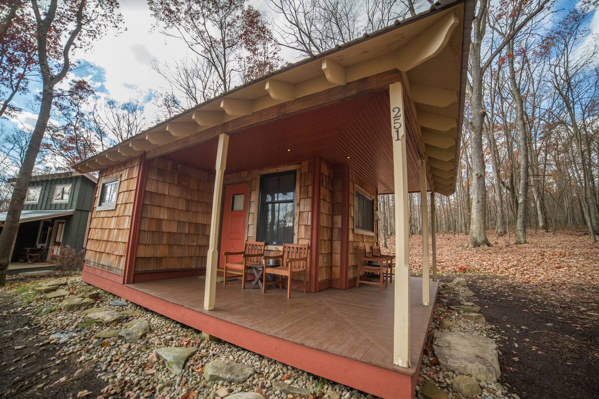 A wooden cabin with a porch, stone pathway, and a number '21' sign.