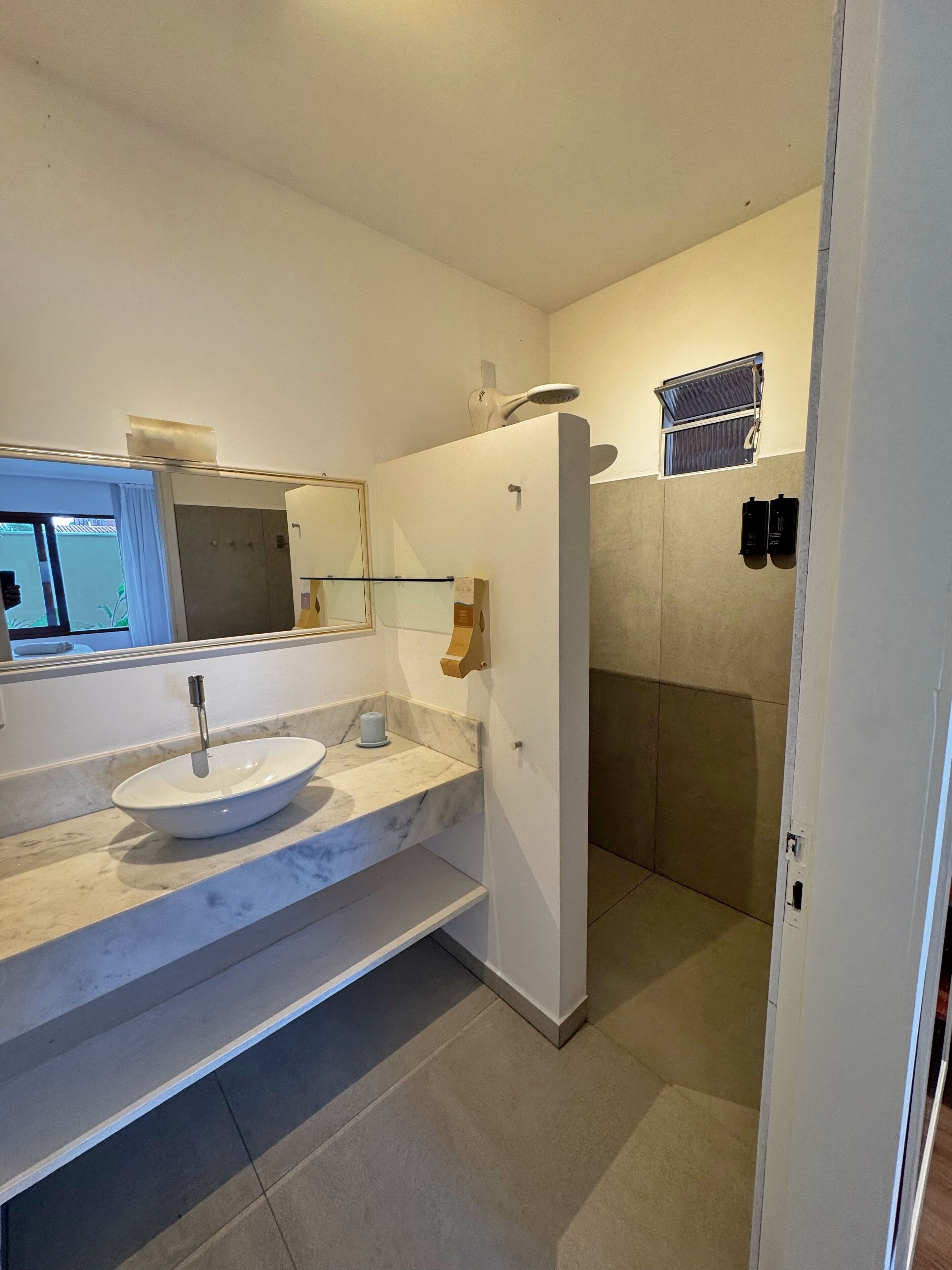 A modern bathroom with a white sink, a mirror, and a shower area.