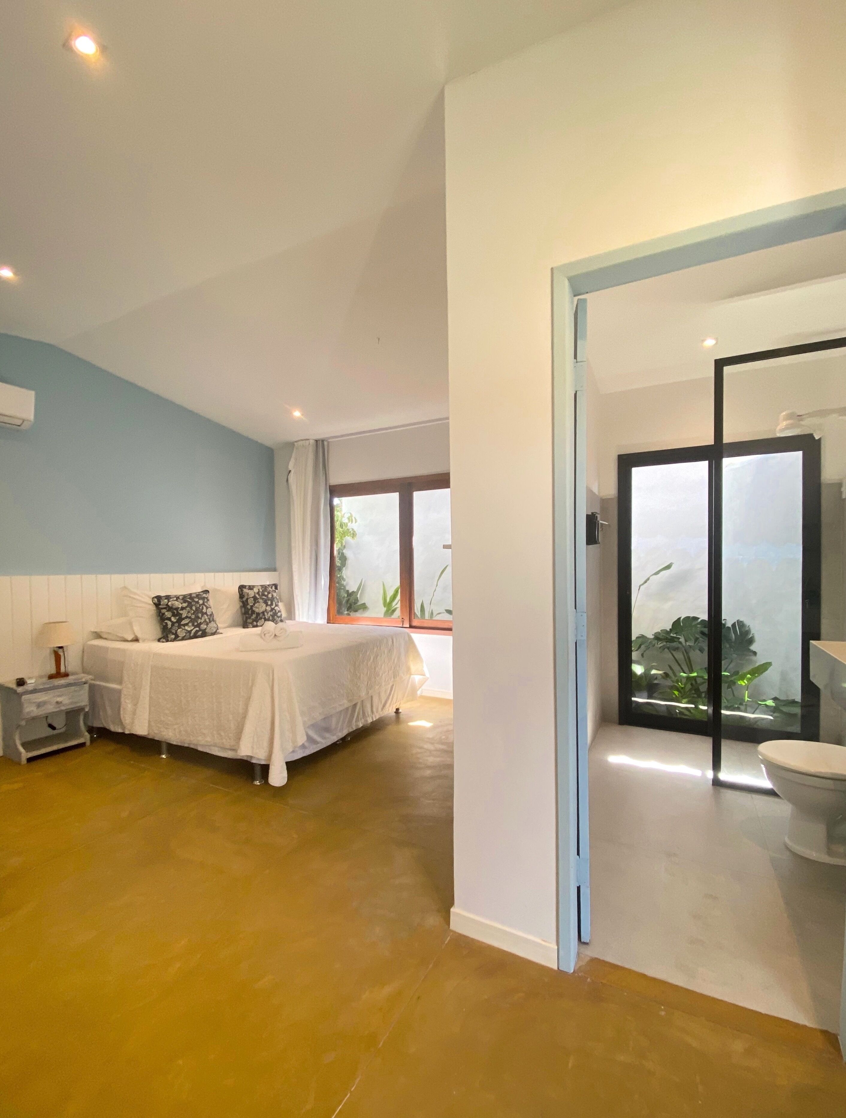 A bedroom with a bed, bedside table, and a view of a bathroom through an open door.