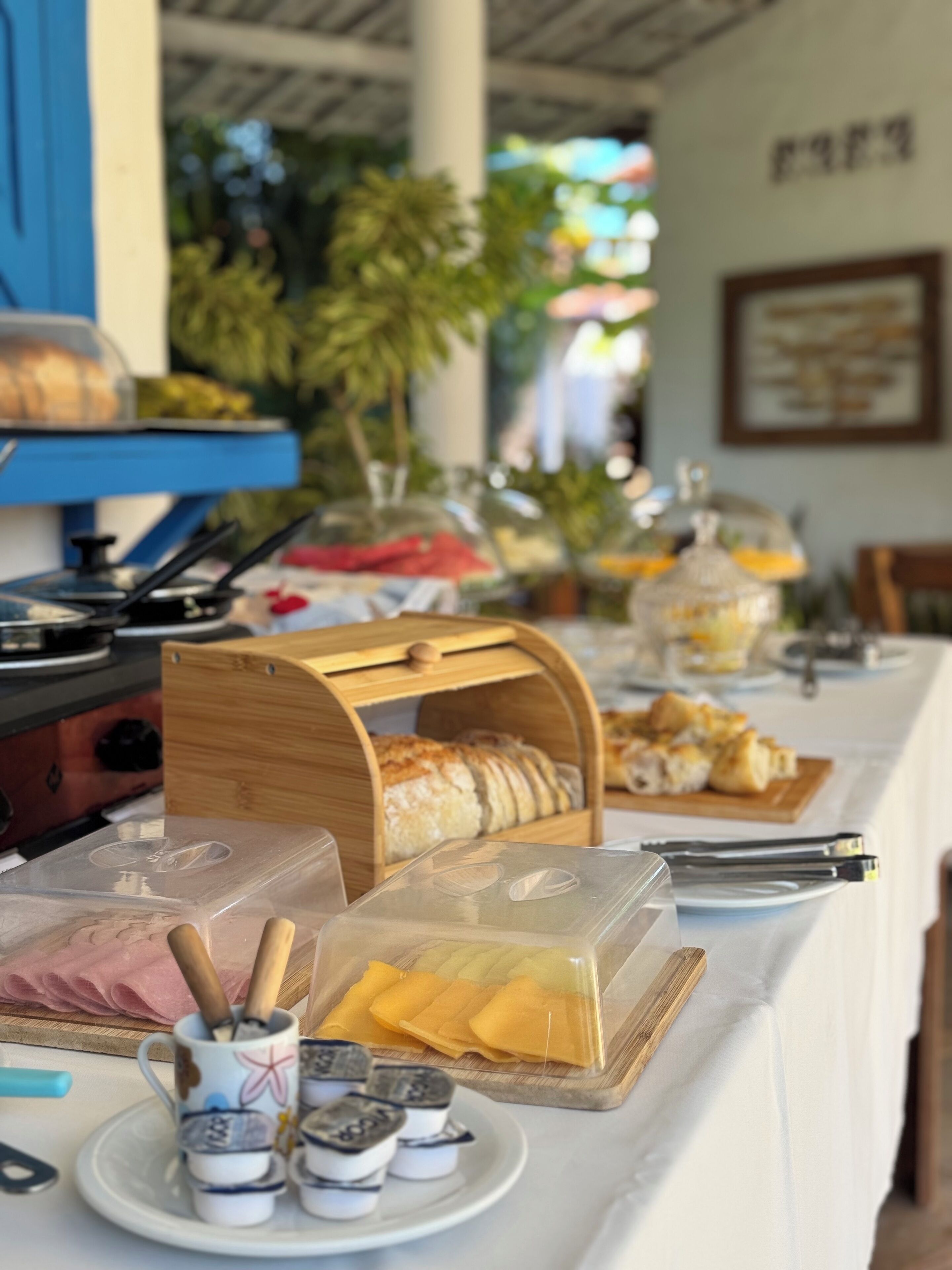 Una taula de buffet amb diversos plats, incloent un aparador de pa, una bandeja de fruita i un recipient amb pastissos.