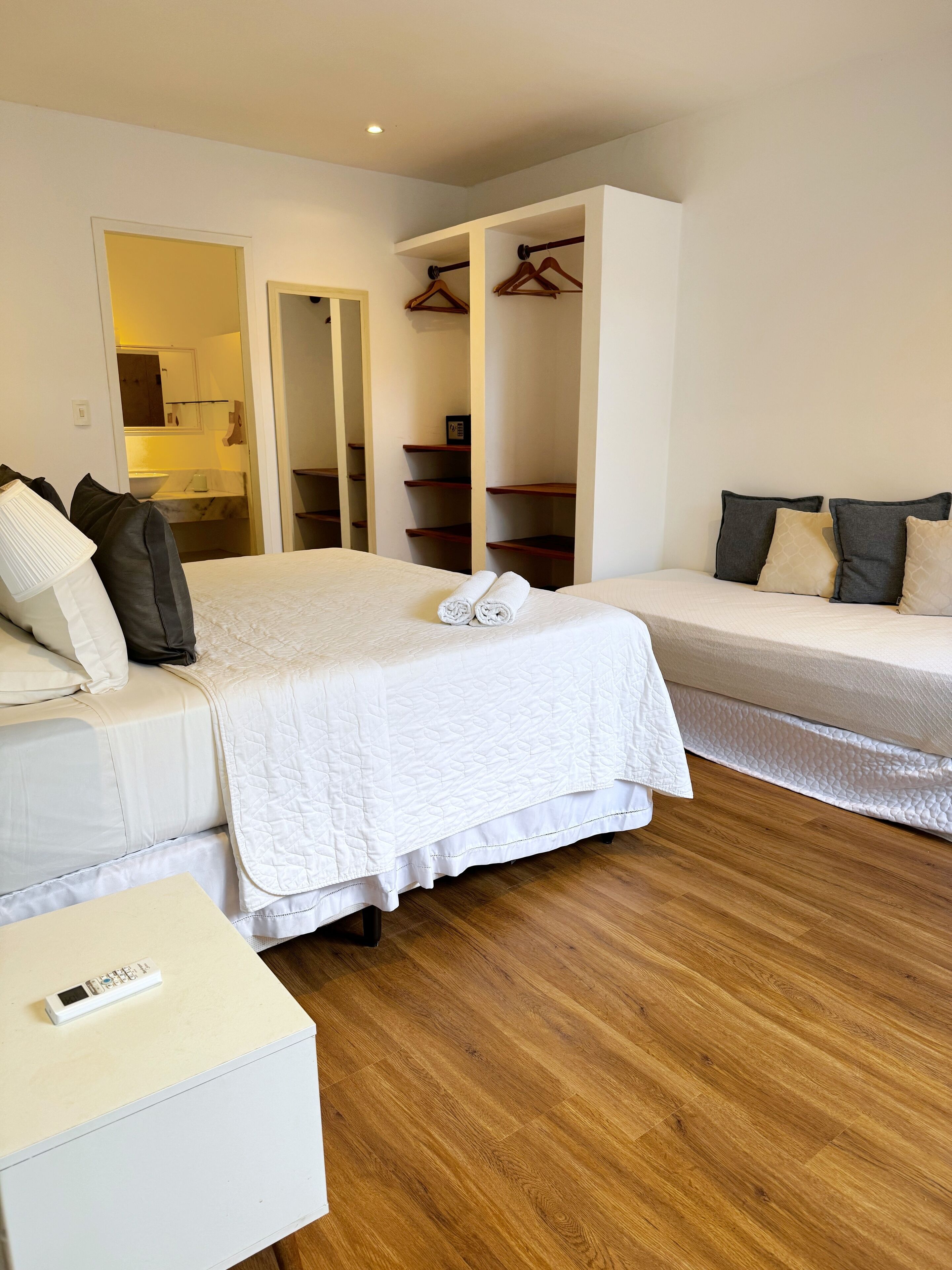 A bedroom with a bed, a bedside table, a wardrobe, and a bathroom visible through an open door.