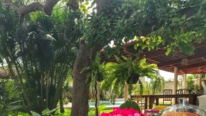 An outdoor dining area with a table set for breakfast, including waffles, fruit, and a covered dish. - Pousada Ilha do Vento (São Miguel do Gostoso)