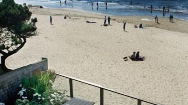 A beach view with a patio area featuring a table and chairs. - Land's End at Cannon Beach (Cannon Beach)