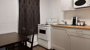 Una kitchenette compacta con estufa, microondas y cafetera.