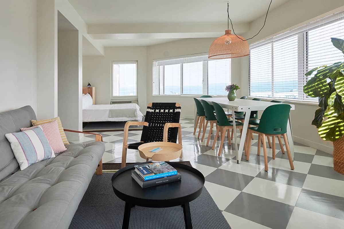 A modern living room with a sofa, dining table, chairs, and a coffee table.