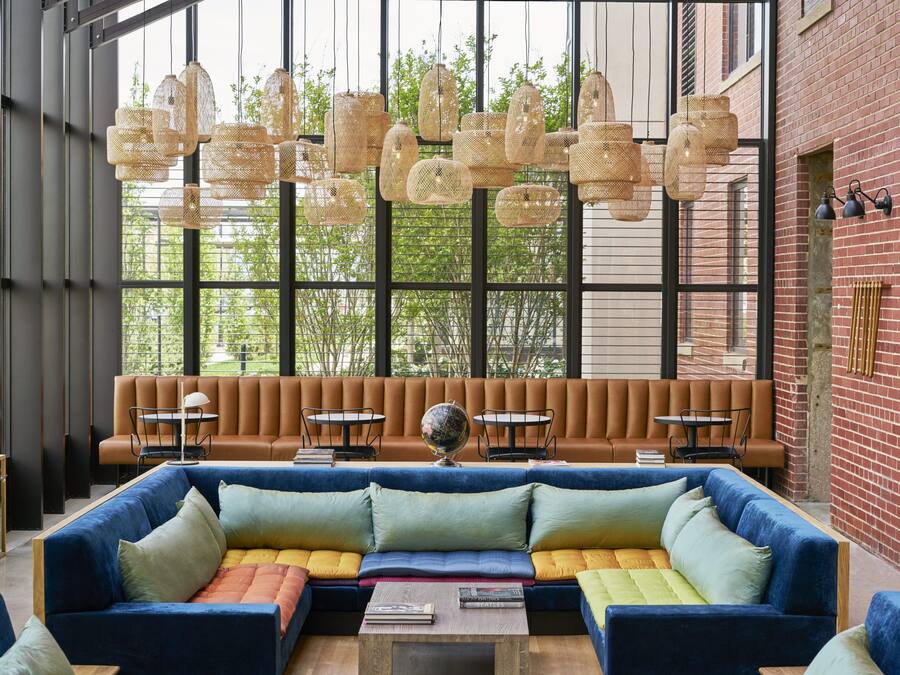 A modern interior with a large blue sectional sofa, a brown leather bench, and a round table with a globe.