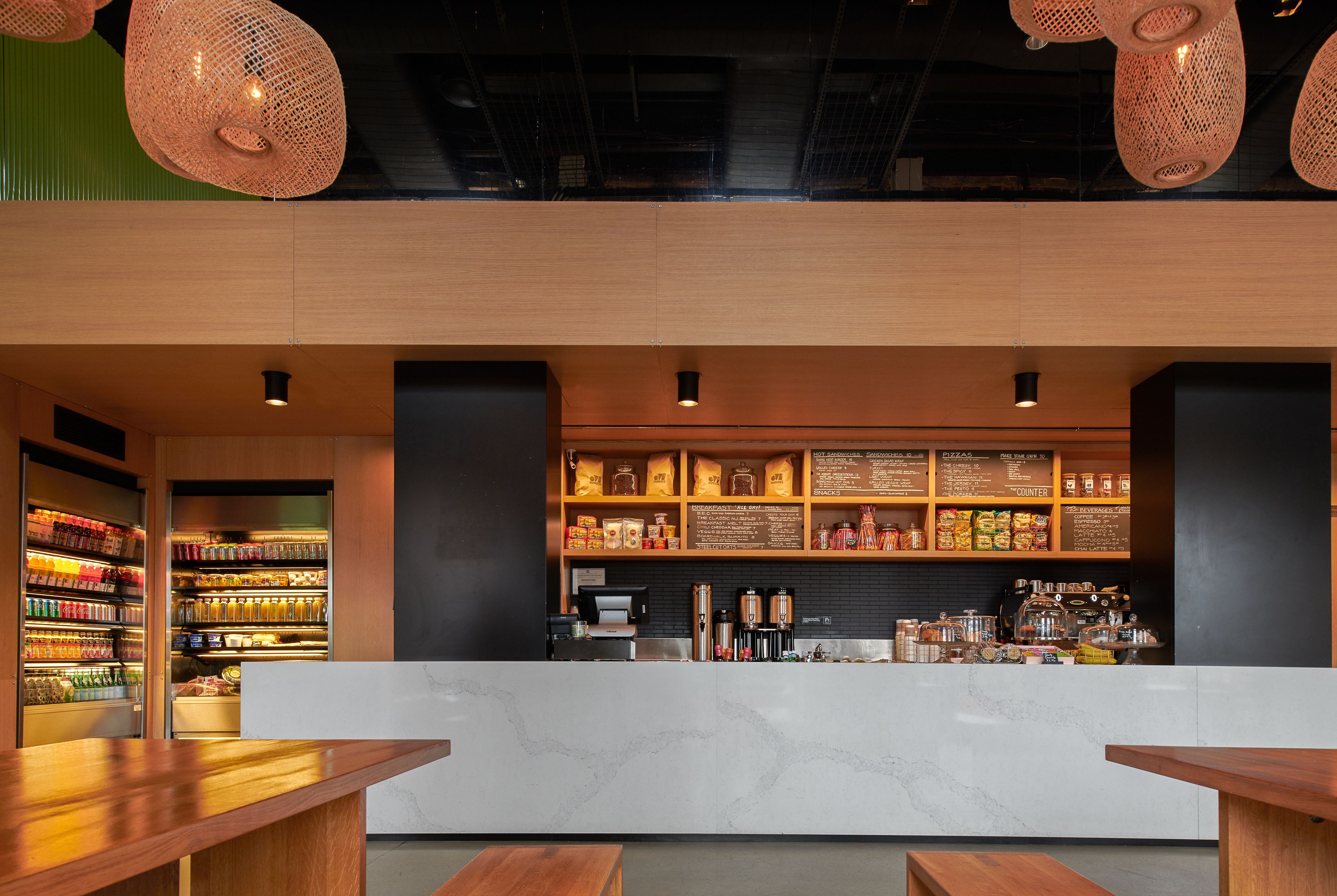 L’intérieur d’un café moderne présente un comptoir en marbre, des tables en bois et une variété de grains de café et de produits exposés sur des étagères.