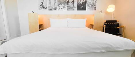 A hotel room with a large bed, a headboard with wall art, bedside lamps, and a checkered floor.