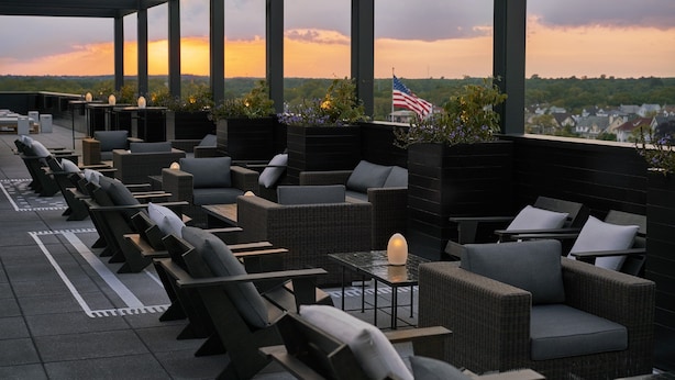 An outdoor seating area with wicker furniture and a view of the sunset. - The Asbury Hotel (Asbury Park)