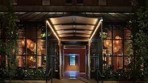A hotel entrance with a covered walkway, glass doors, and a visible reception area. - The Asbury Hotel (Asbury Park)