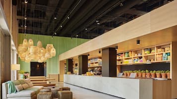 A modern lobby with a reception desk, seating area, and a green wall.