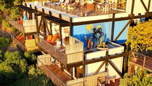 Eine mehrstöckige Holzkonstruktion mit Außenbestuhlung und Wandgemälde.