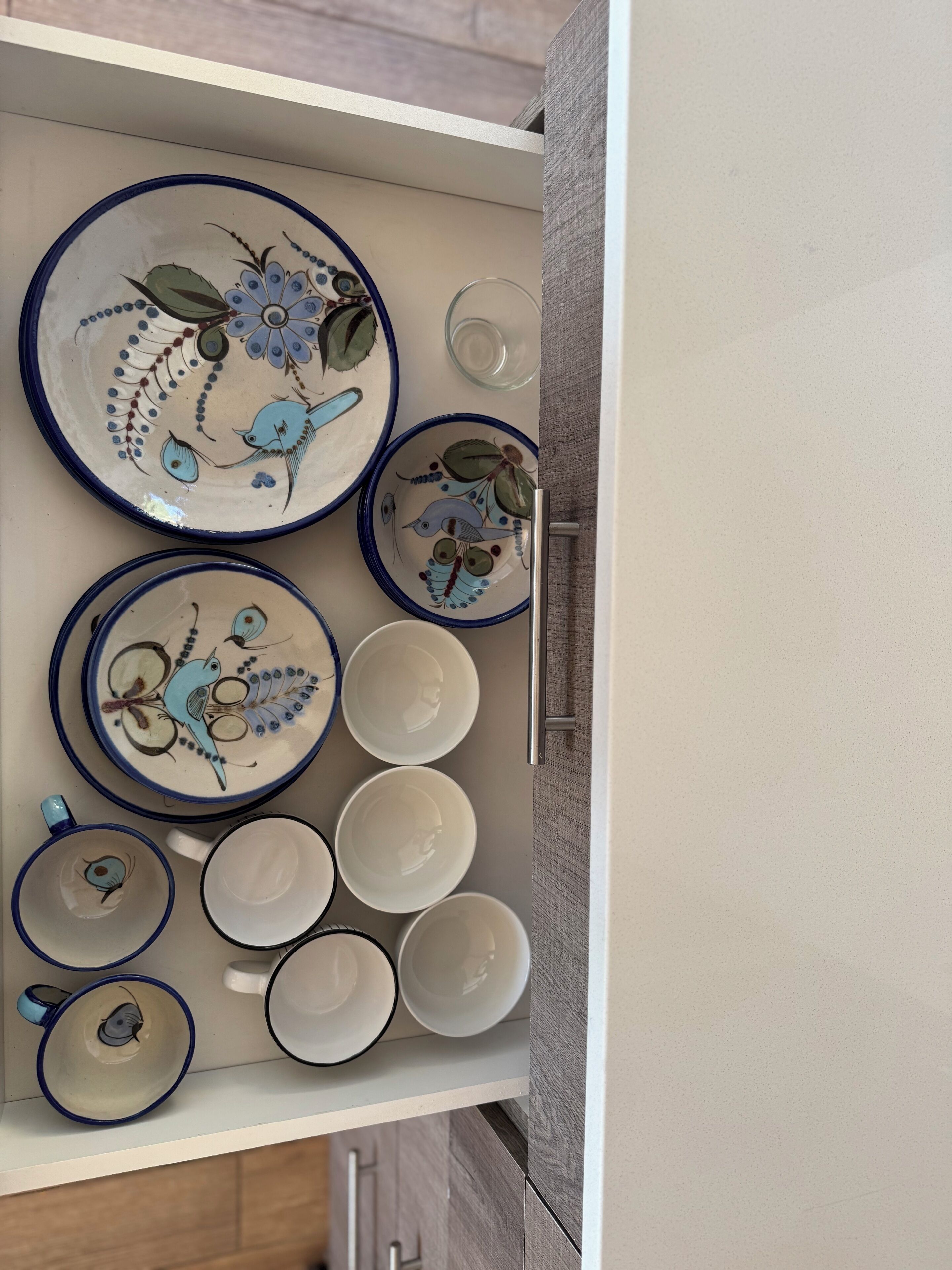 A drawer containing various ceramic dishes and bowls, some with floral designs and others plain.