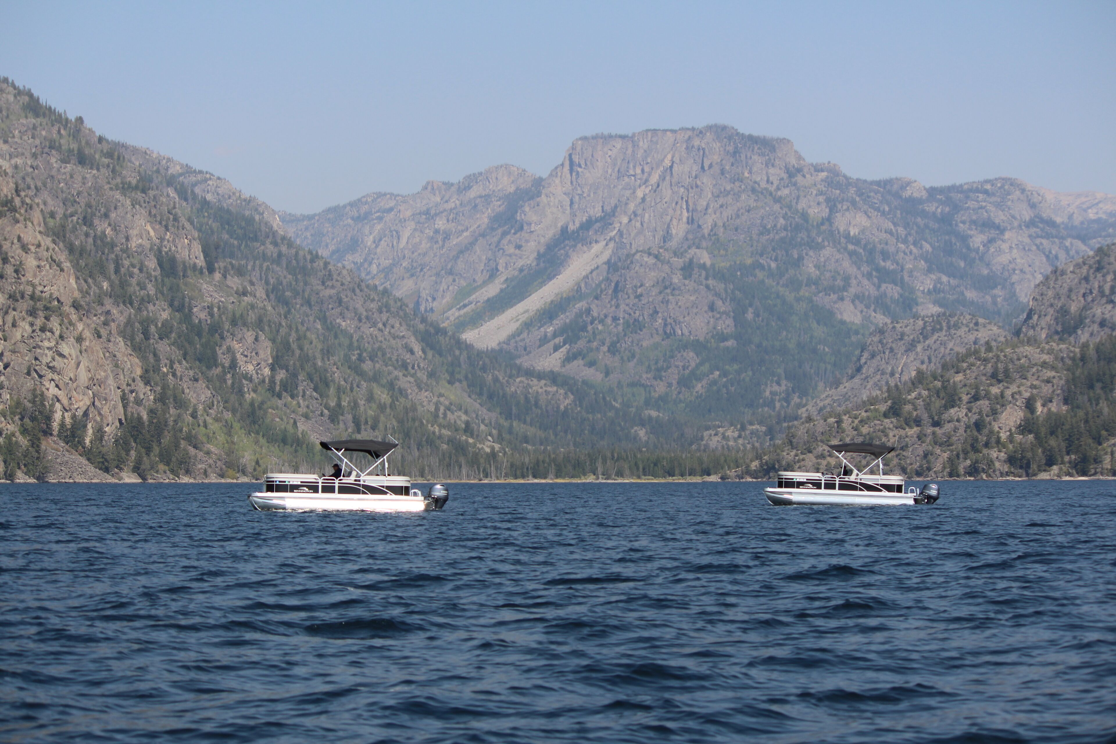 Deux bateaux sur un lac paisible, avec des montagnes en arrière-plan.