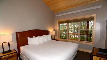 A neatly made bed with white linens, a wooden headboard, and two bedside lamps.