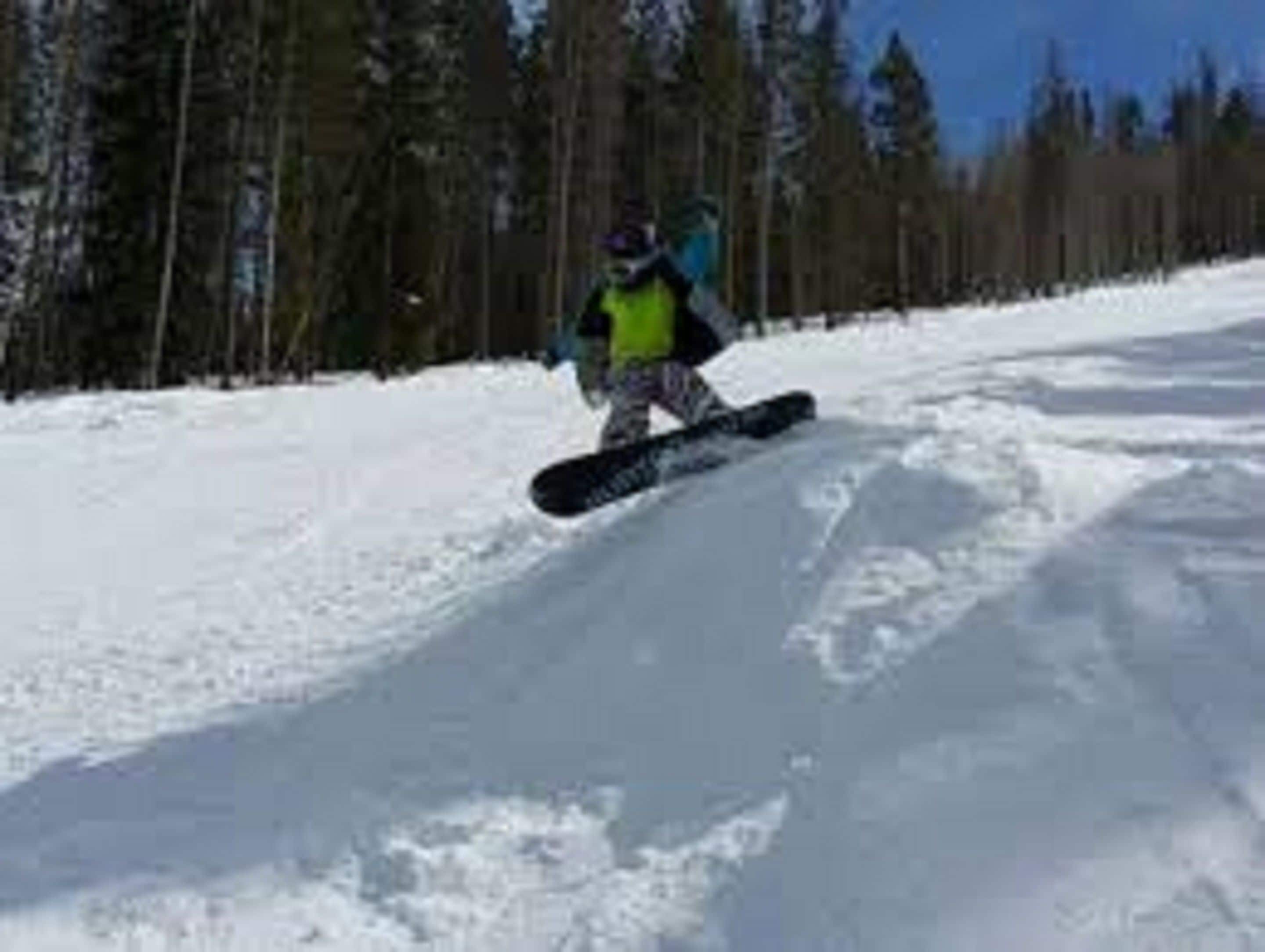 Ein Snowboarder bewegt sich über einen verschneiten Hang.