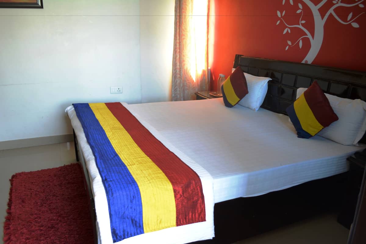 Una cama bien hecha con una colcha a rayas, una alfombra roja y una pared con un mural de un árbol.