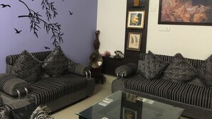 A living room with two sofas, a coffee table, wall decorations including a painting, and an air conditioning unit. - Blessings Jaipur (Jaipur)