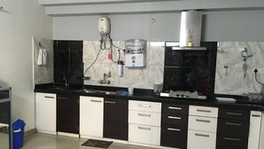A modern kitchen with black and white cabinets, a stainless steel sink, and a built-in range hood. - Blessings Jaipur (Jaipur)