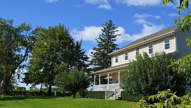 A two-story house with a covered porch and a well-maintained lawn.