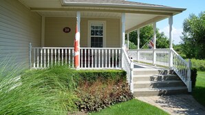 A two-story house with a porch, a number '211' sign, and a flag.