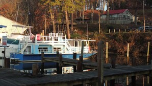 A dock with a boat, a wooden pier, and a house with a red roof in the background. - MV GiaMaria (Richmond)