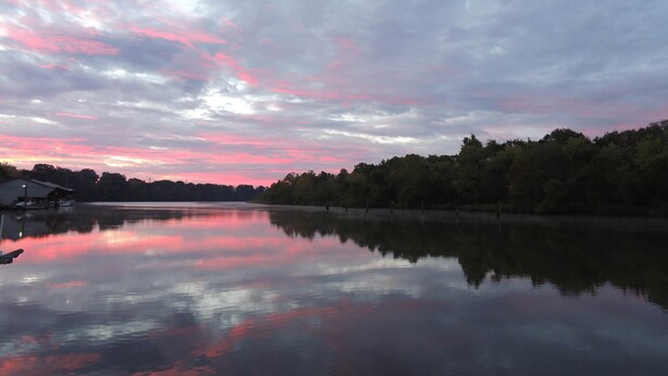 A calm lake with a dock and a small building, surrounded by trees. - MV GiaMaria (Richmond)
