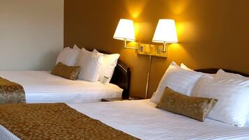 Habitación de hotel con dos camas, una colcha grande, dos lámparas de noche y suelo alfombrado.