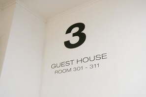 Een muur met een groot cijfer '3' en tekst die aangeeft 'GUEST HOUSE ROOM 301 - 311'.