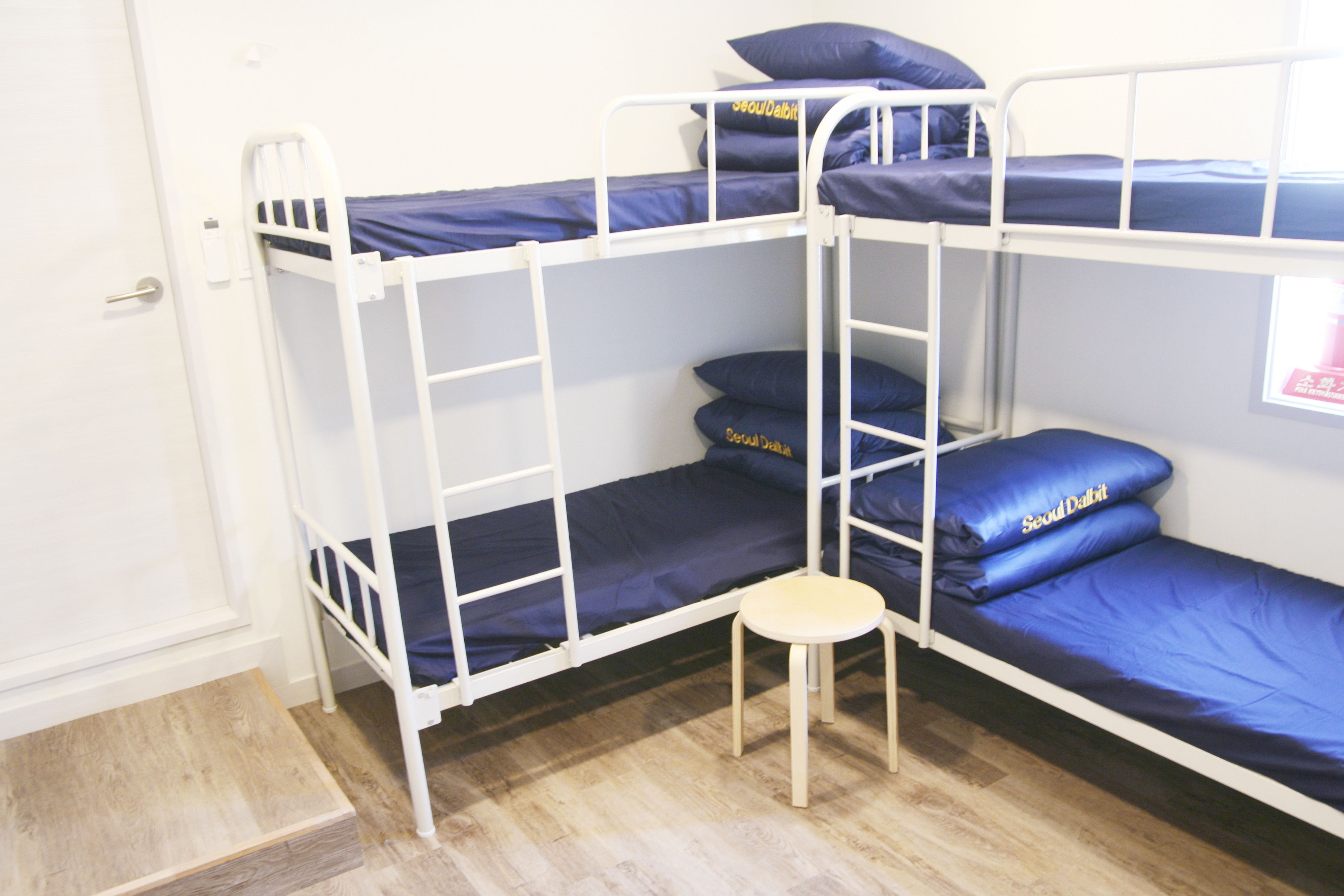 A bunk bed room with a small wooden stool and a door.