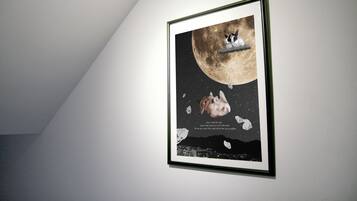 A framed artwork of a rabbit on a moon with a cityscape at the bottom.