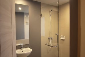 A modern bathroom with a glass-enclosed shower, a sink, and a mirror. - A Bizz (Lampang)