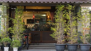A restaurant with a covered entrance, potted plants, and a bicycle parked outside.