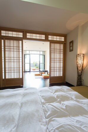 A traditional Japanese room with tatami flooring, a low table, and sliding doors leading to an outdoor area. - Eureka Fucheng Guesthouse (Tainan)