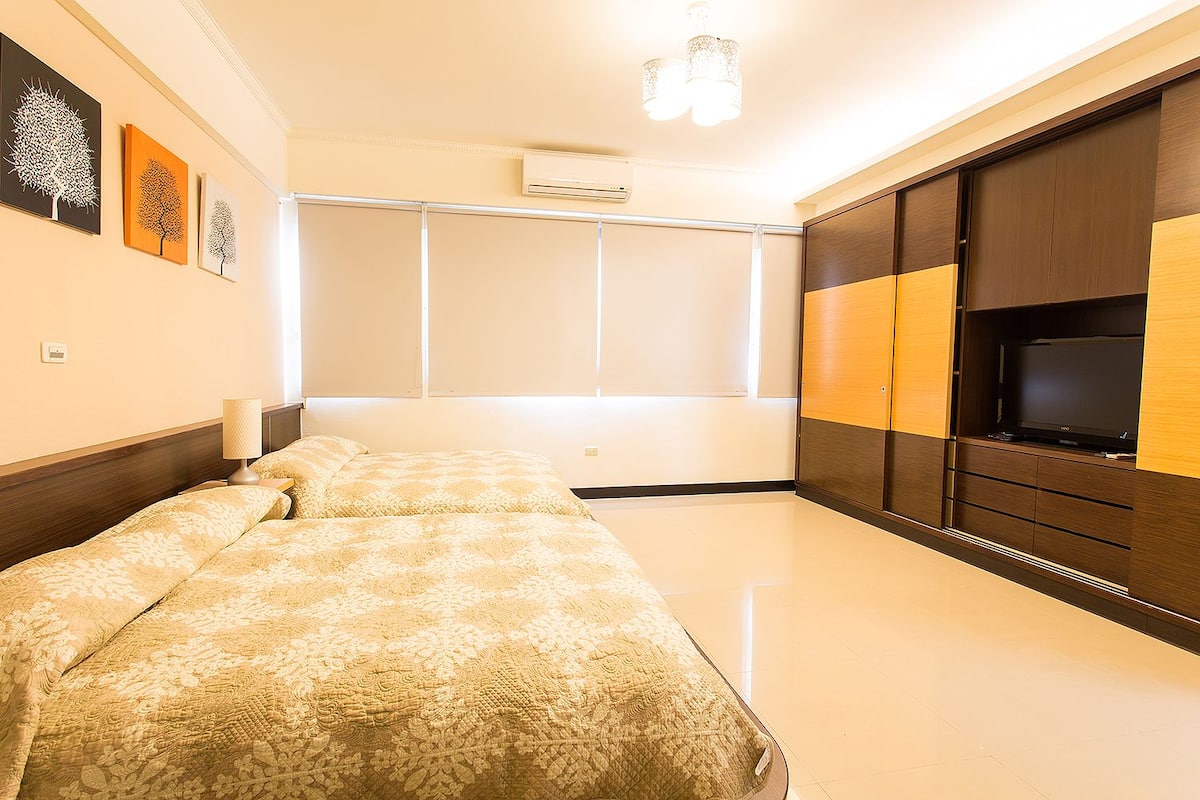 Quarto com cama, televisão e guarda-roupa.