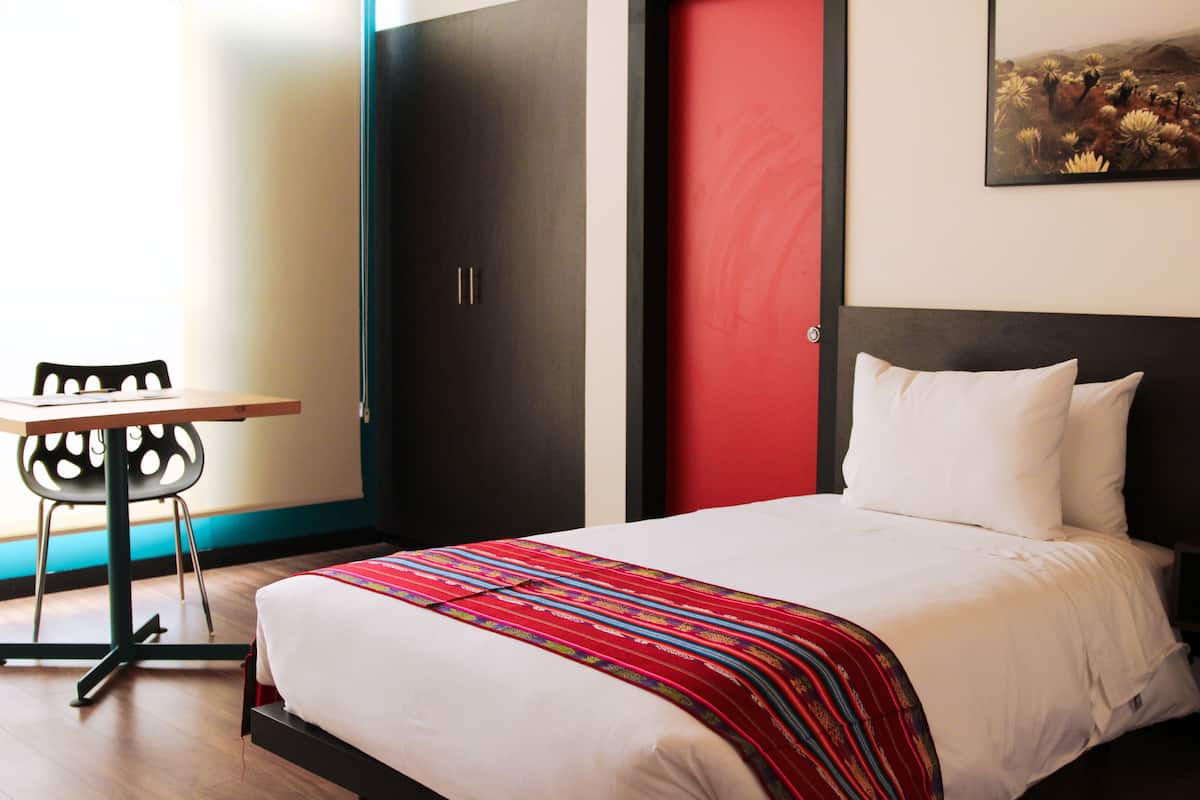 A hotel room with a bed, a desk, and a chair.
