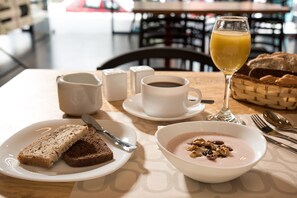 A breakfast setting with bread, coffee, and a glass of orange juice on a table.