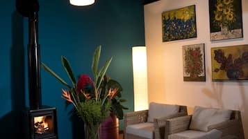 A cozy living room with a fireplace, wicker furniture, and wall art.