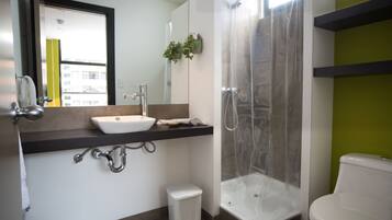 A modern bathroom with a white sink, mirror, and toilet.