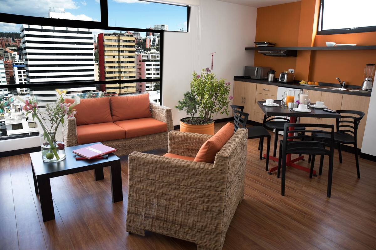 A modern living room with wicker furniture, a dining area, and a kitchen.