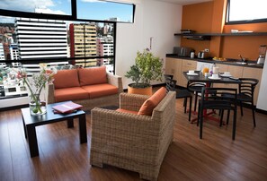 A modern living room with wicker furniture, a dining area, and a kitchen.